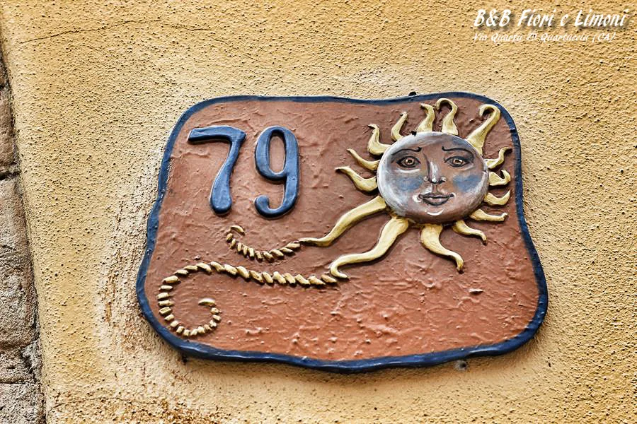 La targa in ceramica con il numero 79 e il sole all'ingresso